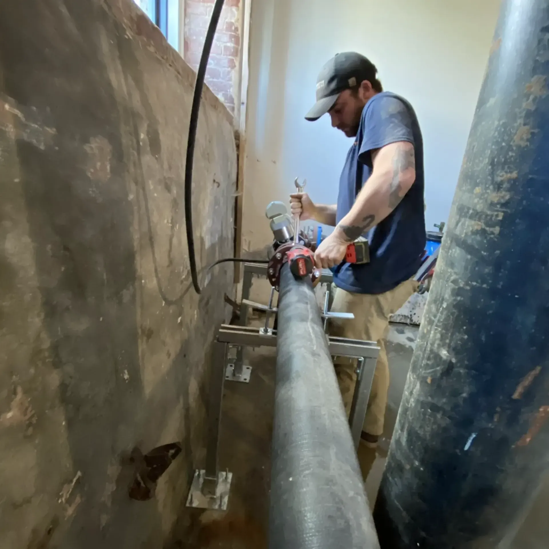 Professional plumber working on pipe with drill